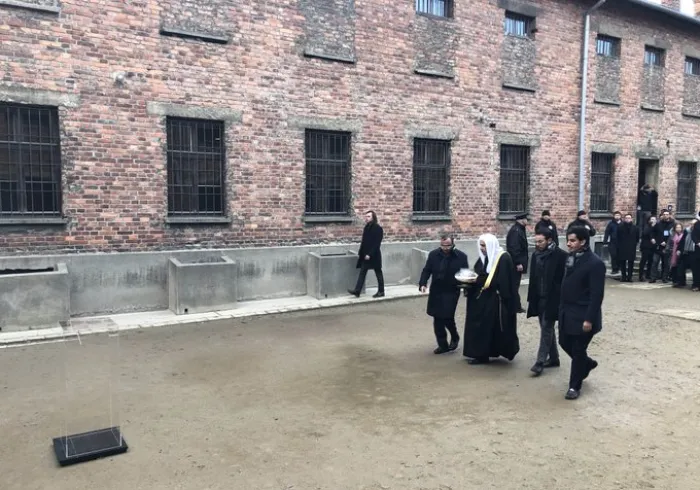 HE Dr. Mohammad Alissa lights a candle at the Wall of Executions in memory of all those killed there while visiting Auschwitz Museum with delegates from AJCGlobal
