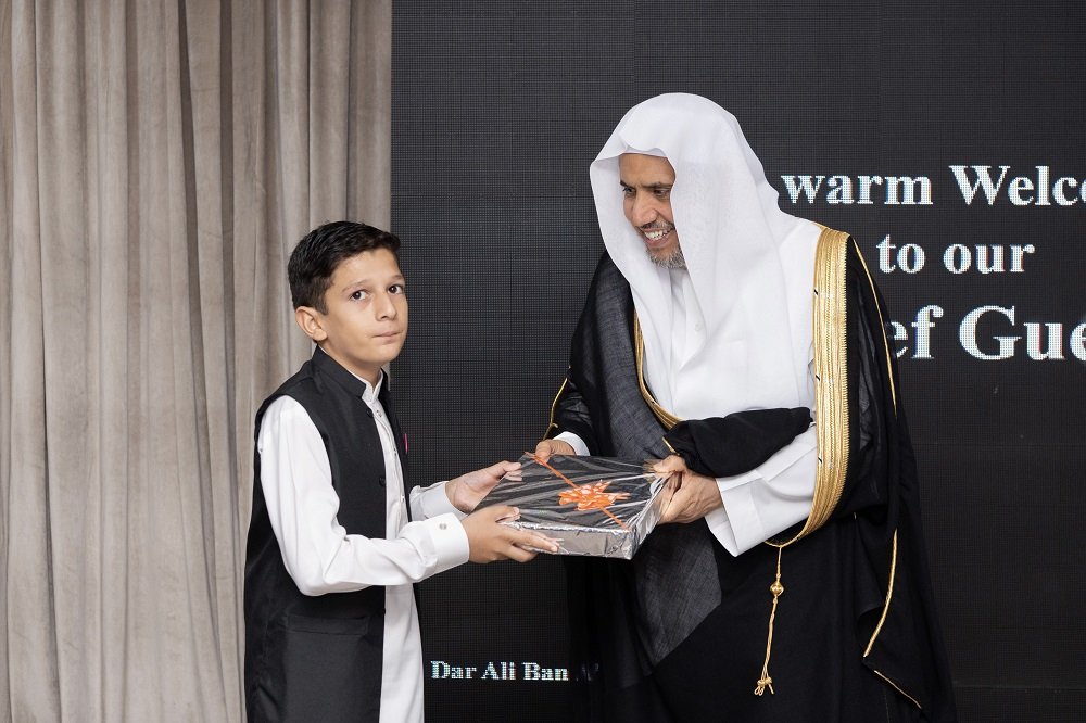 د. العيسى مع أحد أبناءه الإيتام الذين تكفلهم رابطة العالم الإسلامي.